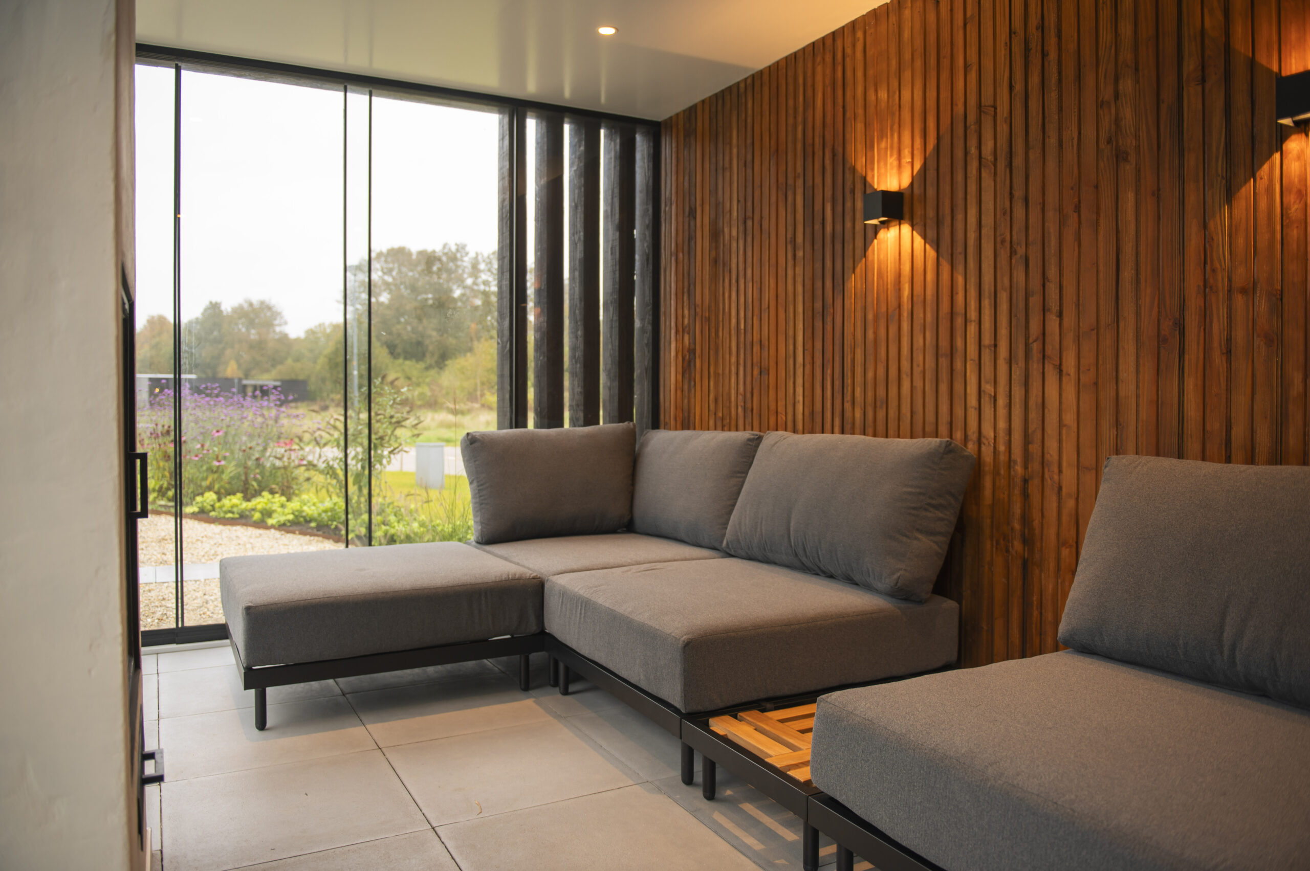 Luxe houten tuinkamer met glazen schuifpuien en houten wand